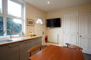 a kitchen with a wooden table and a television on the wall at Vas' York House in York