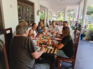 a group of people sitting around a table eating food at Ritigala Hideaway in Habarana