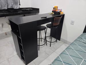 a black desk in a room with two stools at Flat completo a 22 minutos do polo industrial in Aparecida de Goiania