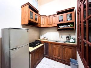 a kitchen with wooden cabinets and a stainless steel refrigerator at Harmadha Villa in Sarangan +7 photos