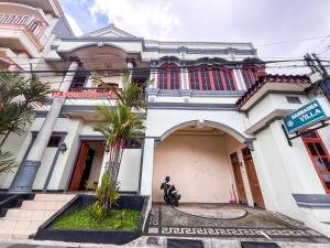 a man sits in front of a building at Harmadha Villa in Sarangan