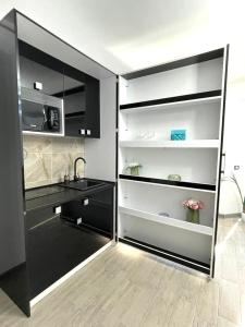 a kitchen with black cabinets and a sink at Nik and dom Alezzi studio in Mamaia Sat/Năvodari