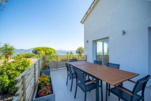 een houten tafel en stoelen op het balkon van een huis bij Villa Joia 2 vue mer 7 chambres in Saint-Tropez