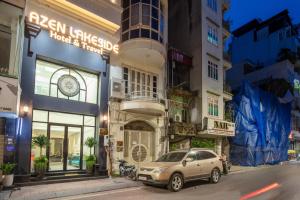 a car parked in front of a building on a street at Azen Lakeside Hotel & Travel in Hanoi