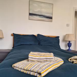 ペイントンにあるPreston Beach Houseの青いシーツと縞模様のタオルが敷かれたベッド