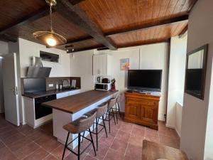 una cucina con bar con sgabelli e televisore di Le cottage des remparts Le triplex a Boulogne-sur-Mer