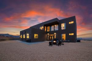a black house in the desert with a sunset at The Highlander - Luxe Hot Tub Firepit Views in Big Water