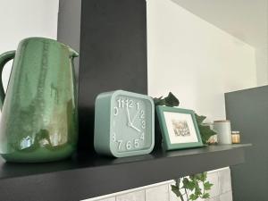 a clock and a vase sitting on a shelf at Upeskrastu mājas in Vilcāni