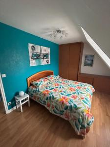 Un dormitorio con una cama y una pared azul. en Gwalarn, en Plouguerneau