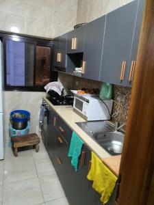 eine kleine Küche mit Spüle und Mikrowelle in der Unterkunft Sicap baobab , Mermoz, Sacré Coeur , Clim, Wifi, Balcon, Dakar in Grand Dakar + 5 Fotos