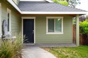 a green house with a black door and a sidewalk at Private Hot-Tub- 3 BDR for 8 Pet's OK in Bend