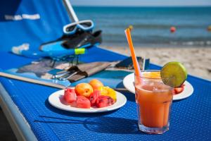 a blue table with a drink and a plate of fruit at Hotel Baia Del Capitano in Cefalù