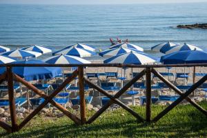 a bunch of blue and white umbrellas on a beach at Hotel Baia Del Capitano in Cefalù
