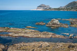 a large body of water with rocks in the water at Hotel Baia Del Capitano in Cefalù