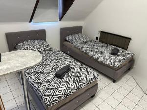 two beds in a small room with a table at Dózsa Vendégház in Balatonboglár