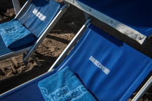 two blue chairs on the beach with a towel on them at Hotel Baia Del Capitano in Cefalù