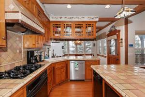 une cuisine avec des armoires en bois et un four à plaques de cuisson dans l'établissement Matternhorn Peak Lodge - For 10, à Lake Arrowhead