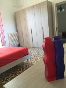 zwei rote und blaue Vasen in einem Zimmer mit einem Bett in der Unterkunft Casa Vacanza CIVICO 33 in Marittima