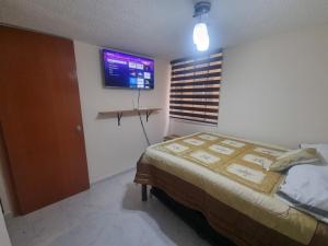 Un dormitorio con una cama y un televisor en la pared. en El depa de Natalia a min de aeropuerto y estadio GNP, en Ciudad de México