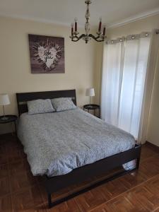 a bedroom with a bed with two night stands and a chandelier at Casa da Praça - Country Residence in Amoreira +19 photos