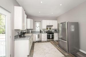 a kitchen with white cabinets and a stainless steel refrigerator at Queen City Grand House in Cincinnati