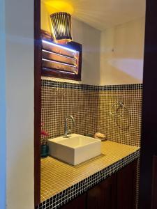 a bathroom with a white sink and black tiles at Wind Village in Itarema +23 photos