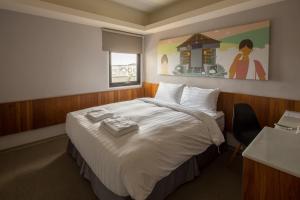 a hotel room with a large bed and a painting on the wall at Meci Hotel in Hualien City