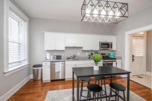 a kitchen with white cabinets and a black table and chairs at Suites on Main 1 in Covington
