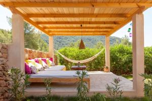 a bed under a wooden pergola with a hammock at Villa Es Coral in Cala Vadella