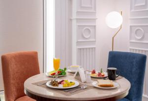 a table with two plates of food and orange chairs at Nars Plus Al Naeem Hotel in Jeddah