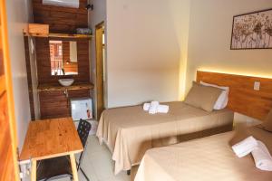 a hotel room with two beds and a table at Hotel Pousada Gavi e Nono in Santa Ernestina +41 photos