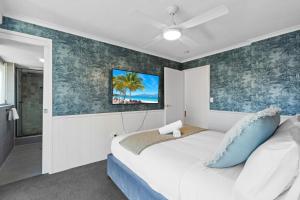 a bedroom with a white bed with a blue accent wall at The Beachside - Fully Renovated 2BR unit with Parking Pool Tennis next to beach and tram in Gold Coast