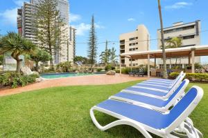 a pair of lounge chairs sitting on the grass near a pool at The Beachside - Fully Renovated 2BR unit with Parking Pool Tennis next to beach and tram in Gold Coast