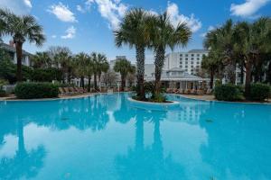 a large swimming pool with palm trees and a building at Seashell Shuffle at Sandestin Pilot House in Destin