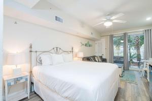 a bedroom with a large white bed with a ceiling fan at Seashell Shuffle at Sandestin Pilot House in Destin