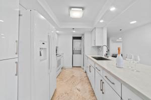 uma cozinha branca com uma pia e uma geladeira em Condo on the Pool - Retreat for 4 with Water Views & Resort-style Amenities em Miami