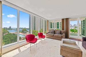 uma sala de estar com um sofá, cadeiras e janelas em Condo on the Pool - Retreat for 4 with Water Views & Resort-style Amenities em Miami