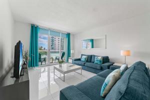 ein Wohnzimmer mit einem blauen Sofa und einem Tisch in der Unterkunft Ocean Wind - Luxury Beachfront Condo with Pool & Gym in Hollywood