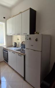 a kitchen with white cabinets and a white refrigerator at Vila Olti in Vlorë +14 photos