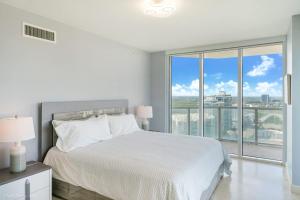 a white bedroom with a bed and a large window at A Breathtaking Oceanview - High Rise Luxury Condo in Sunny Isles Beach +10 photos
