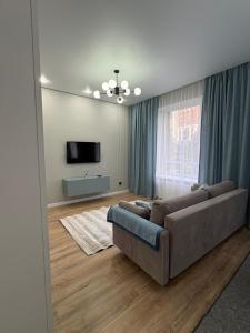 a living room with a couch and a flat screen tv at двухкомнатная студия с красивой набережной in Astana