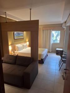 a hotel room with a bed and a couch at Apartamento Suíte Flat Hot Springs Hotel em Caldas Novas com parque aquático in Caldas Novas