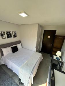 a bedroom with a large white bed and a table at Canto da Praia Balneário Camboriú in Balneário Camboriú