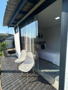 a bedroom with a bed and two chairs on a deck at Canto da Praia Balneário Camboriú in Balneário Camboriú