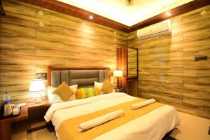 une chambre avec un grand lit et des murs en bois dans l'établissement A P Palace Hotel, à Ayodhya
