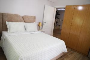 een slaapkamer met een wit bed en een houten kast bij Shtepi Pushimi Alesjo in Korçë