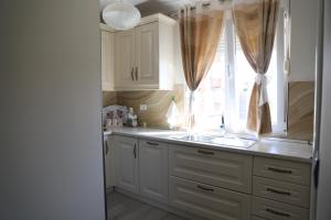 een keuken met witte kasten, een gootsteen en een raam bij Shtepi Pushimi Alesjo in Korçë