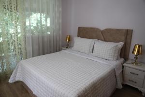 een slaapkamer met een wit bed en een raam bij Shtepi Pushimi Alesjo in Korçë