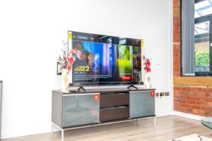 een flatscreen-tv op een stand in een woonkamer bij Sampaul Bradford Apartment in Bradford