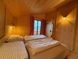 two beds in a wooden room with a window at Langegger Alm - Sennerstube in Helmenstein +28 photos